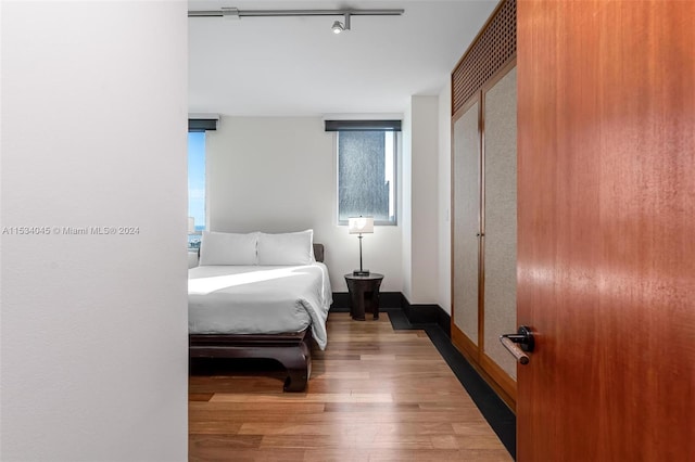 bedroom featuring a closet, rail lighting, and light wood-type flooring