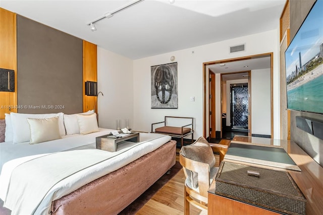 bedroom with track lighting and light hardwood / wood-style floors