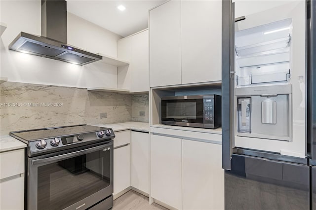 kitchen with white cabinets, wall chimney exhaust hood, tasteful backsplash, and stainless steel appliances