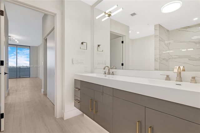 bathroom featuring floor to ceiling windows, large vanity, dual sinks, and wood-type flooring