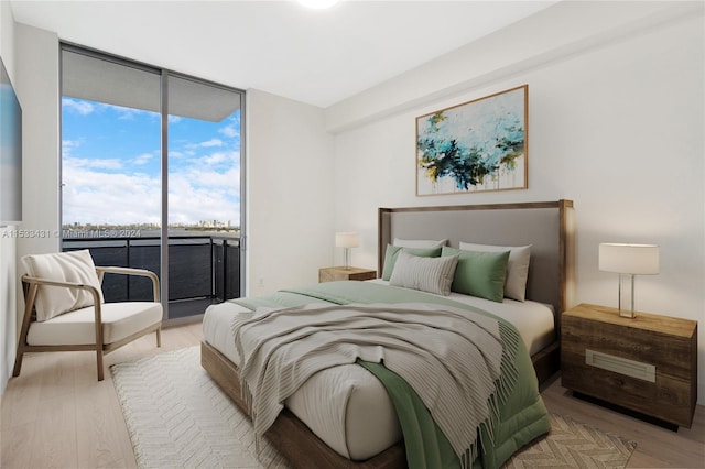 bedroom featuring floor to ceiling windows, access to exterior, and light wood-type flooring