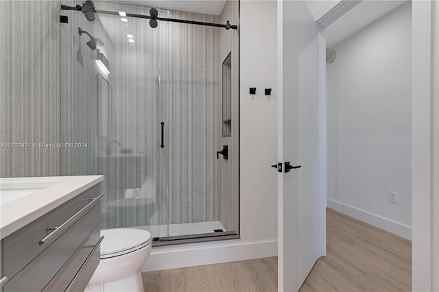 bathroom with vanity, a shower with door, hardwood / wood-style floors, and toilet