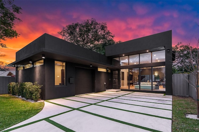 back house at dusk with a patio area and a lawn