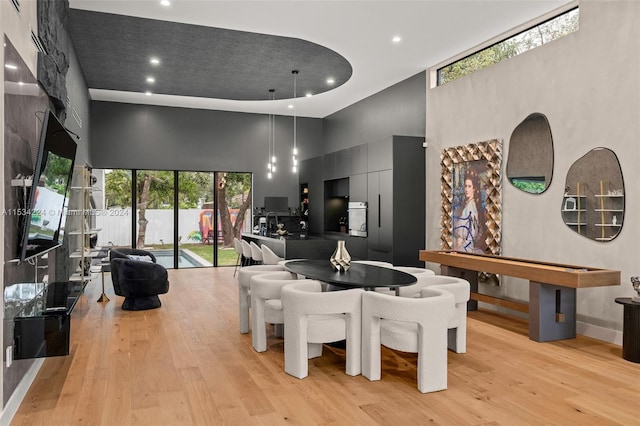 dining room with a high ceiling and light hardwood / wood-style floors