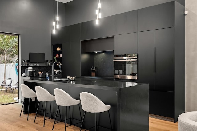 kitchen featuring an island with sink, a breakfast bar, and light wood-type flooring