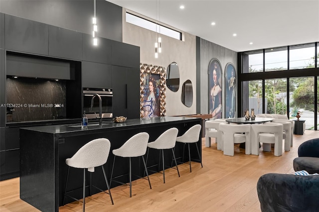 kitchen featuring light hardwood / wood-style floors, a kitchen island with sink, a breakfast bar area, and sink