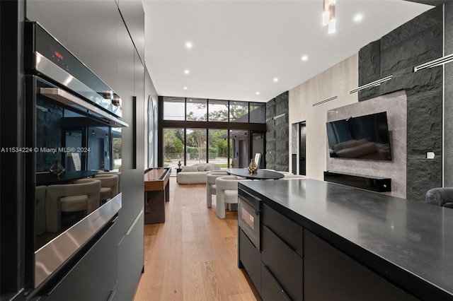 kitchen featuring a high ceiling, stainless steel double oven, and light wood-type flooring