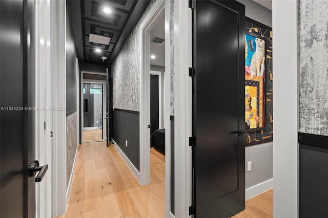 hall featuring coffered ceiling and light hardwood / wood-style flooring