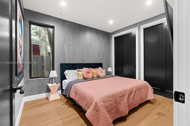 bedroom featuring multiple closets and light hardwood / wood-style flooring