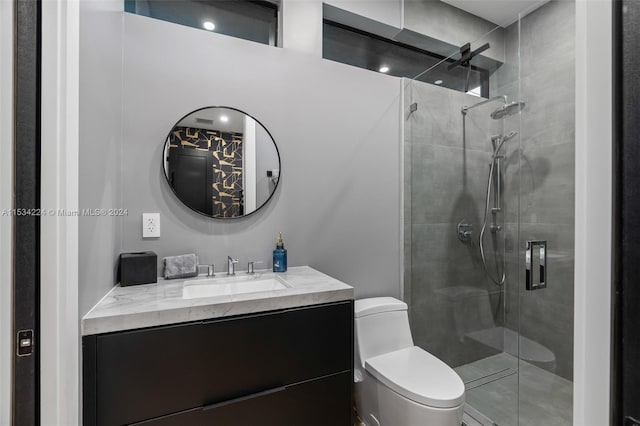 bathroom with vanity, a shower with door, and toilet