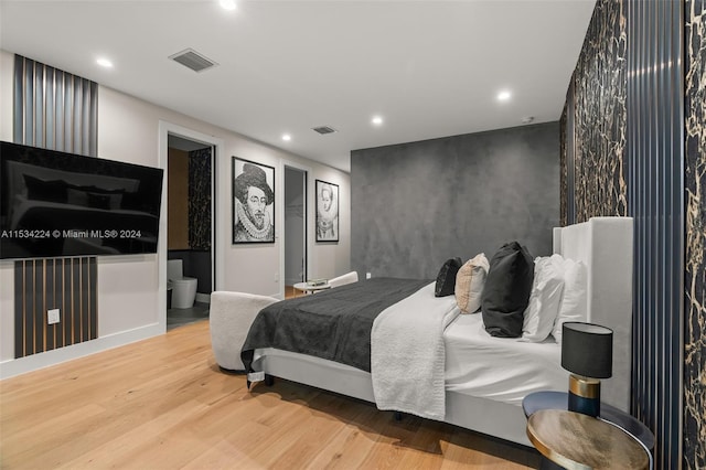 bedroom featuring ensuite bath and light wood-type flooring