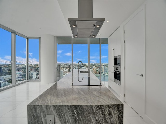 kitchen featuring white cabinets, plenty of natural light, and island range hood