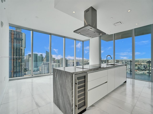 kitchen with light tile floors, ventilation hood, dark stone countertops, white cabinets, and beverage cooler