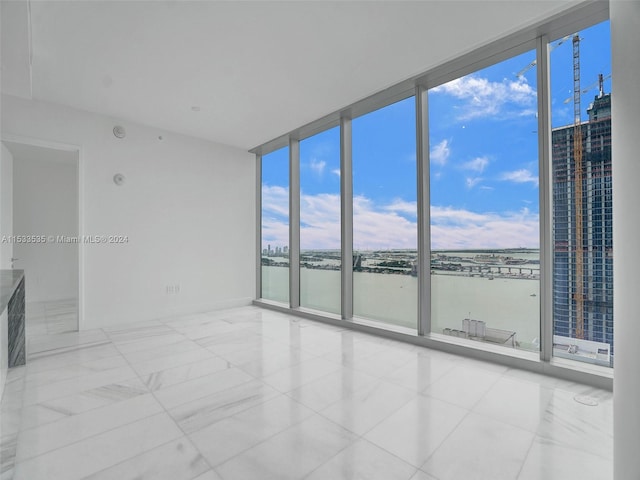 empty room featuring plenty of natural light, expansive windows, and light tile flooring