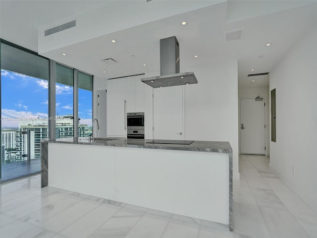 kitchen with light tile floors, white cabinets, dark stone countertops, and island exhaust hood