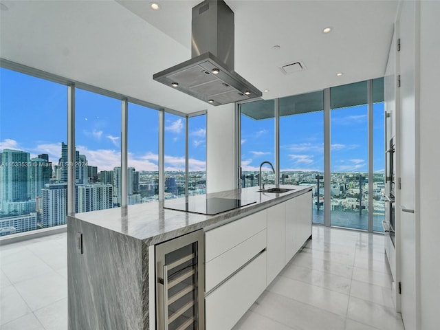 kitchen with light tile floors, beverage cooler, white cabinets, island exhaust hood, and sink