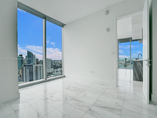 tiled spare room featuring expansive windows and sink