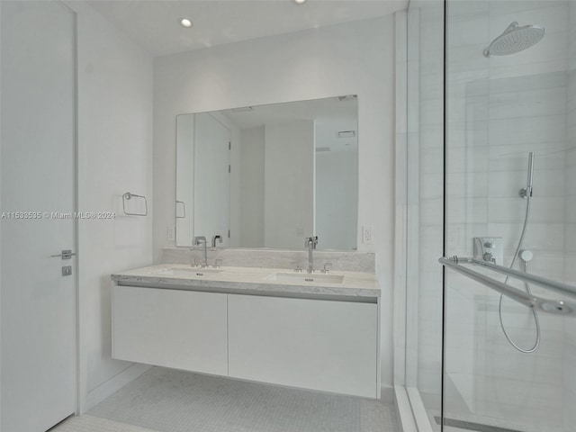 bathroom featuring tile floors, a shower with shower door, dual sinks, and large vanity