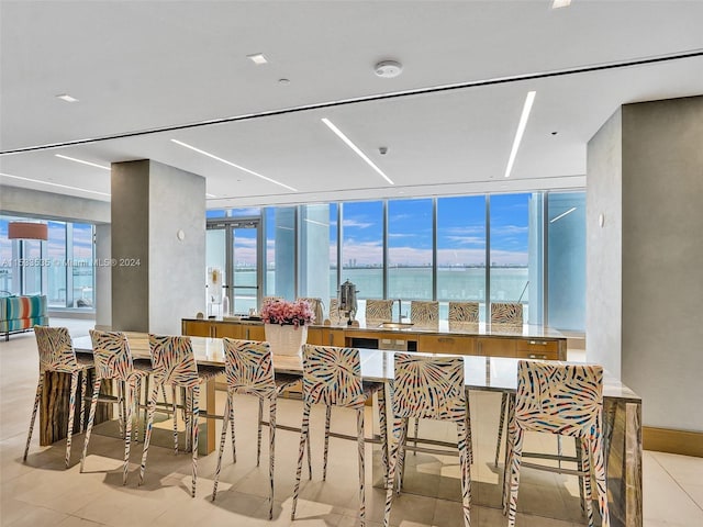 tiled dining room featuring a water view, expansive windows, and plenty of natural light