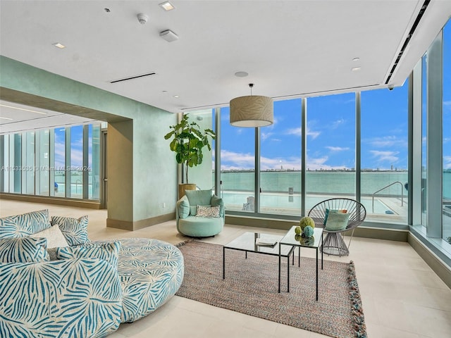 living room with a water view, light tile floors, and a wall of windows