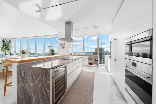 kitchen with white cabinetry, light tile patterned flooring, a breakfast bar, island range hood, and beverage cooler