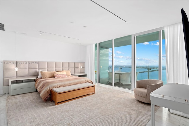 bedroom with floor to ceiling windows, access to exterior, and a water view