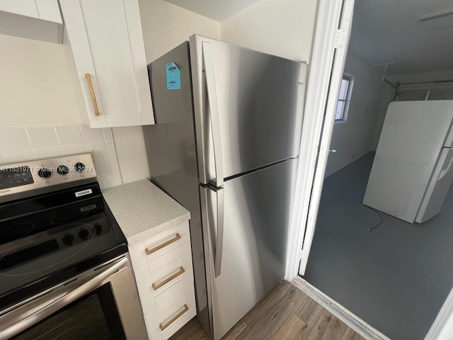 kitchen featuring backsplash, light hardwood / wood-style floors, stainless steel appliances, and white cabinets