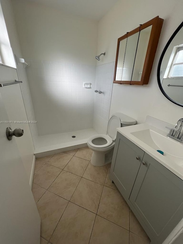 bathroom featuring vanity, tile floors, toilet, and tiled shower