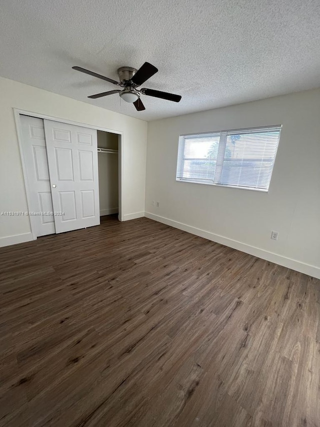 unfurnished bedroom with dark hardwood / wood-style floors, a textured ceiling, a closet, and ceiling fan