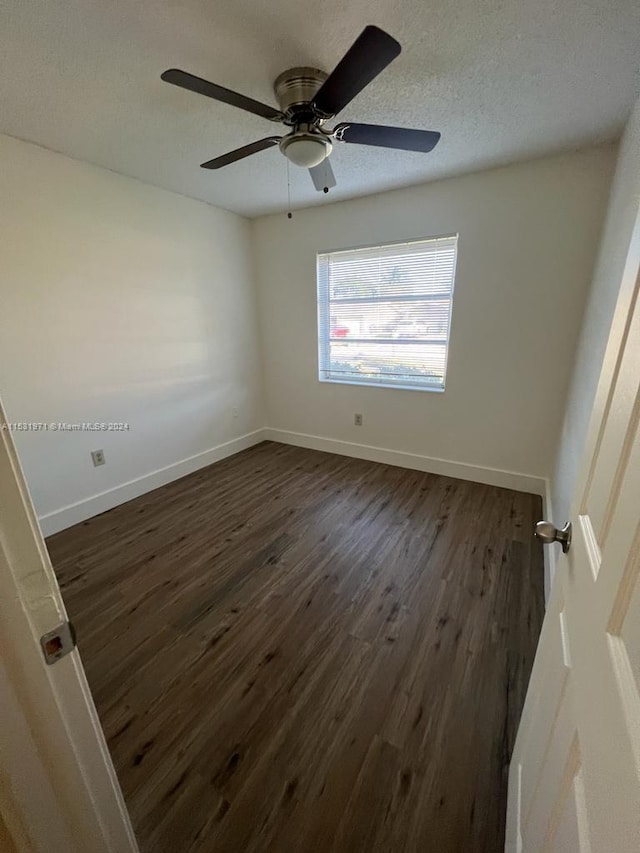 empty room with ceiling fan and dark wood-type flooring