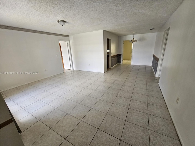 tiled empty room with a textured ceiling and an inviting chandelier