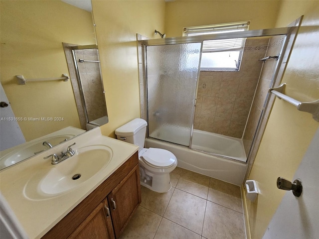 full bathroom with toilet, tile floors, vanity with extensive cabinet space, and shower / bath combination with glass door