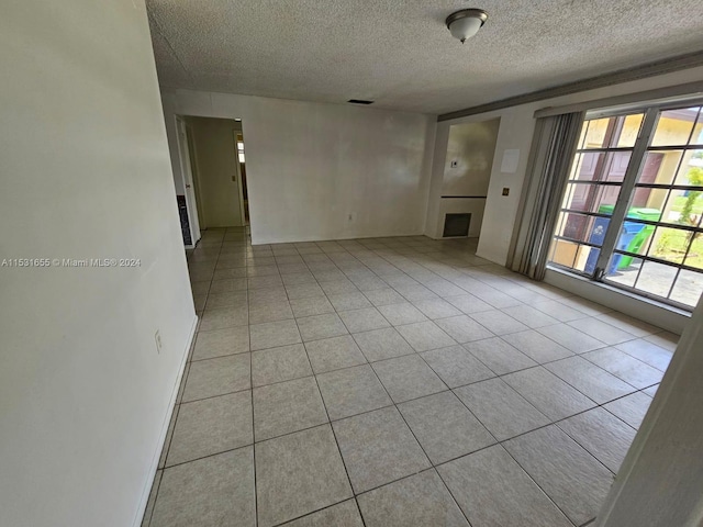 spare room with a textured ceiling and light tile floors