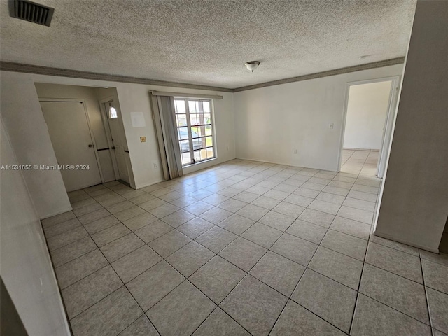 spare room featuring crown molding, a textured ceiling, and light tile floors