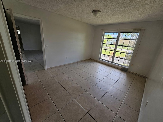 tiled spare room with a textured ceiling