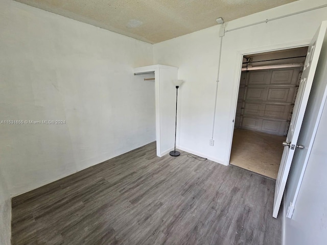 unfurnished bedroom with a textured ceiling, a closet, and dark wood-type flooring