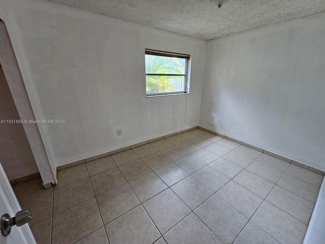 unfurnished room featuring light tile floors and a textured ceiling