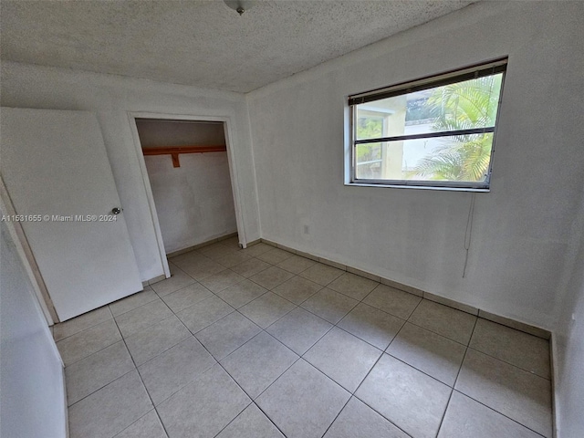 unfurnished bedroom with a closet, a textured ceiling, and light tile flooring