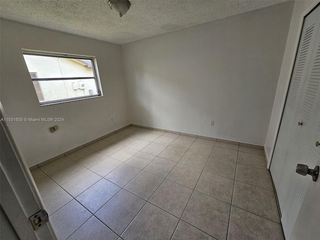 tiled spare room with a textured ceiling