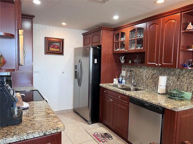 kitchen with sink, light tile floors, light stone counters, appliances with stainless steel finishes, and tasteful backsplash