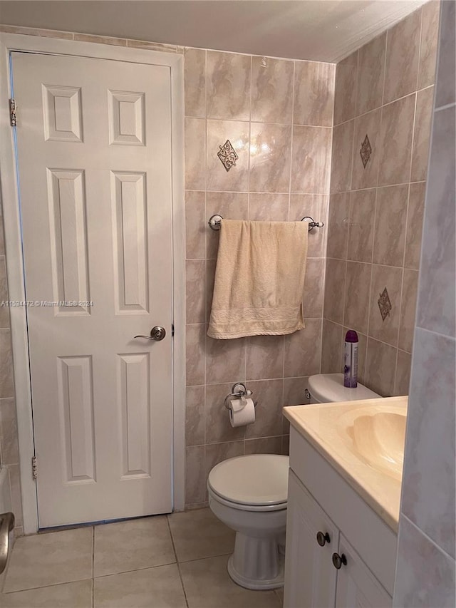 bathroom featuring vanity, tile flooring, toilet, and tile walls