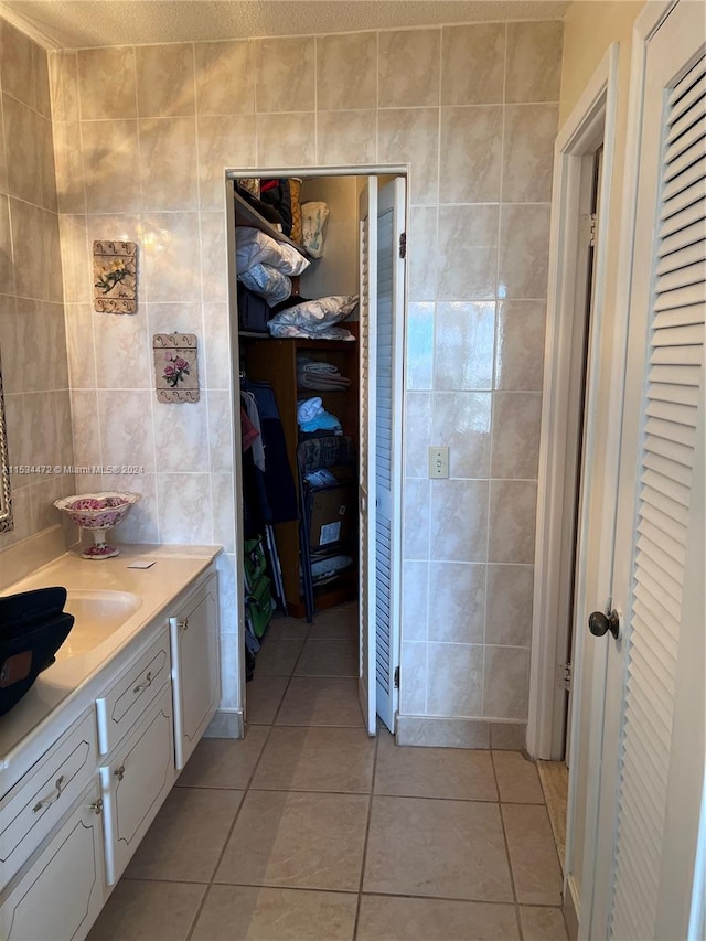 bathroom with tile walls, tile floors, and vanity