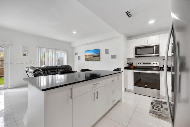 kitchen featuring white cabinetry, a center island, light tile patterned floors, and appliances with stainless steel finishes