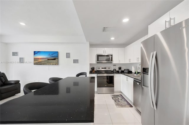 kitchen with appliances with stainless steel finishes, light tile patterned floors, and white cabinetry