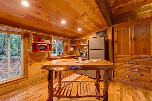 dining room with light wood-type flooring, wood ceiling, sink, and wooden walls