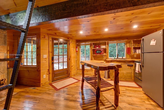 dining space featuring sink, wooden walls, light hardwood / wood-style flooring, built in shelves, and wood ceiling