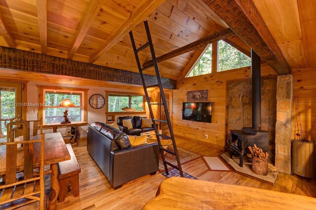 living room with beam ceiling, light hardwood / wood-style floors, a wood stove, and wood ceiling