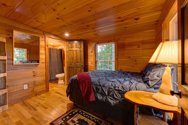 bedroom featuring ensuite bath, wooden walls, wooden ceiling, and light wood-type flooring