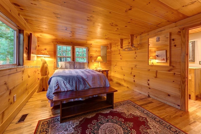 bedroom featuring ensuite bathroom, light hardwood / wood-style flooring, and wood ceiling