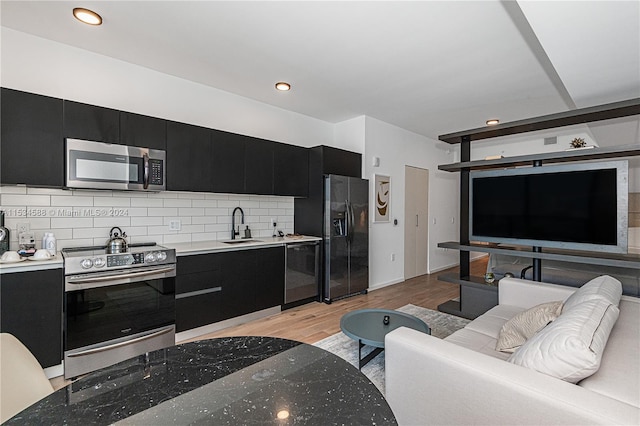 kitchen featuring tasteful backsplash, light hardwood / wood-style flooring, appliances with stainless steel finishes, and sink